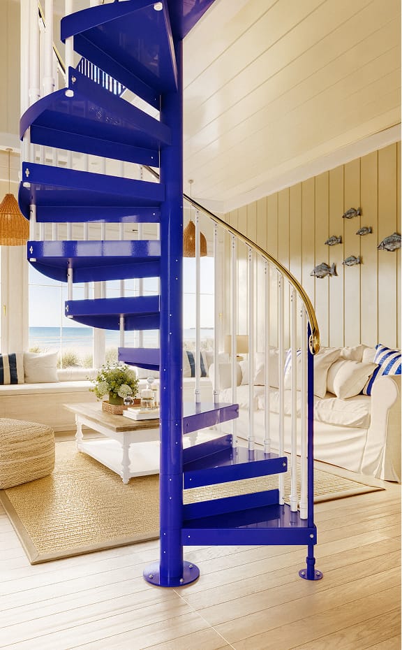 Cobalt blue powder-coated spiral staircase with white spindles in a coastal living room overlooking the ocean