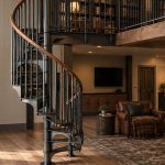 American Industrial spiral staircase with a wood handrail in a barndominium home library loft with built-in bookshelves