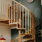 Carpenter spiral staircase with oak spindles and handrail curving down from the loft landing
