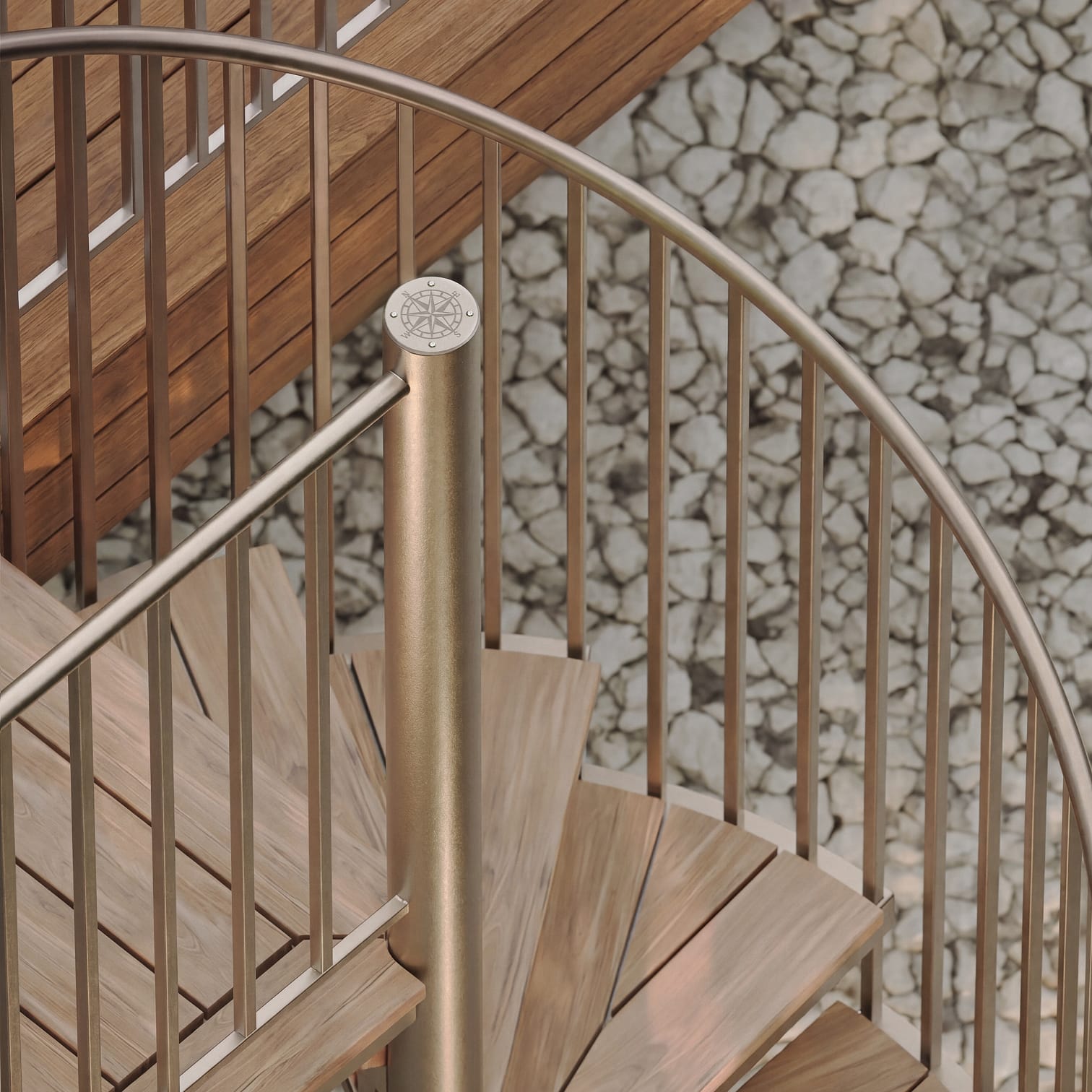 Overhead close-up of a bronze metal spiral staircase with teak treads and a compass medallion on the center post, above a stone mosaic floor