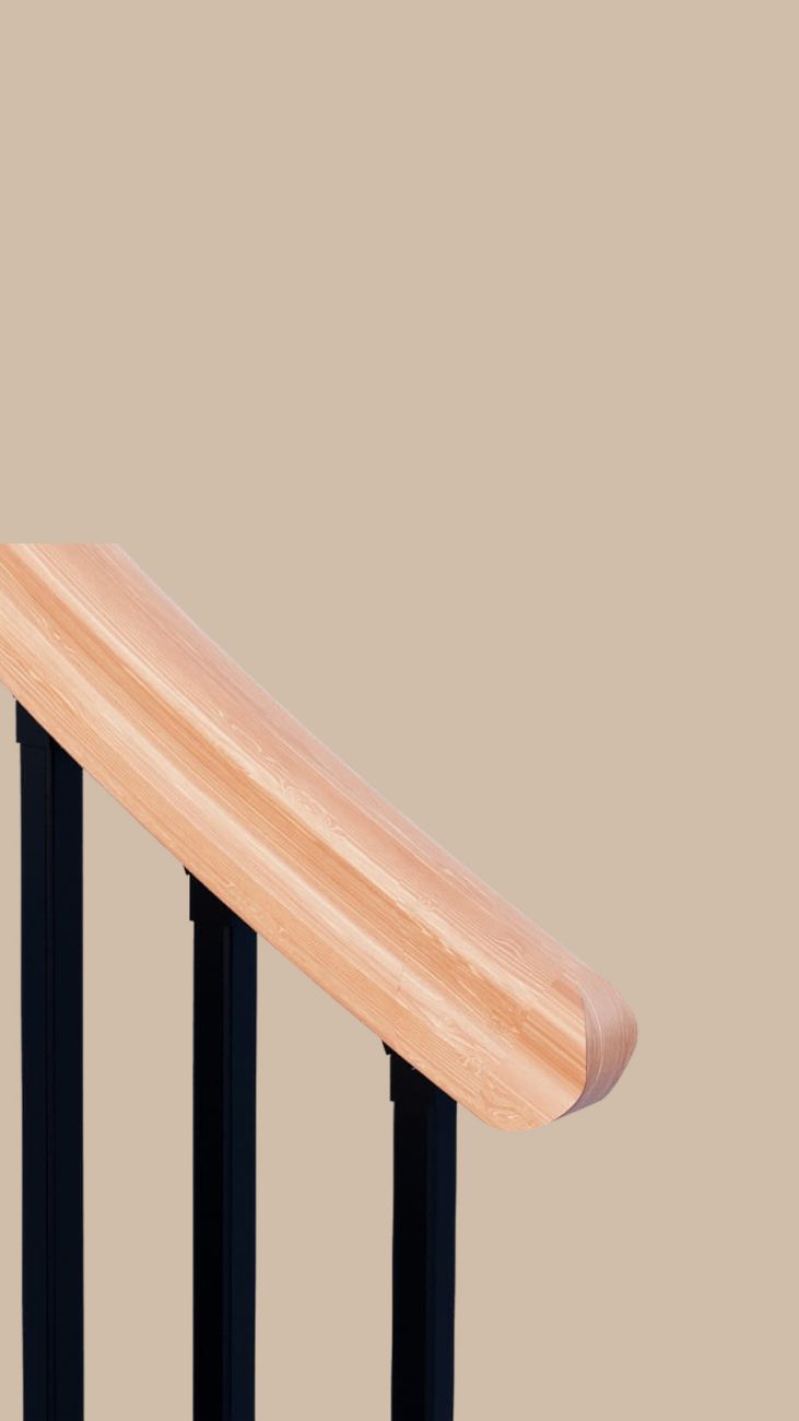 Close-up of a wood handrail profile on black metal spindles