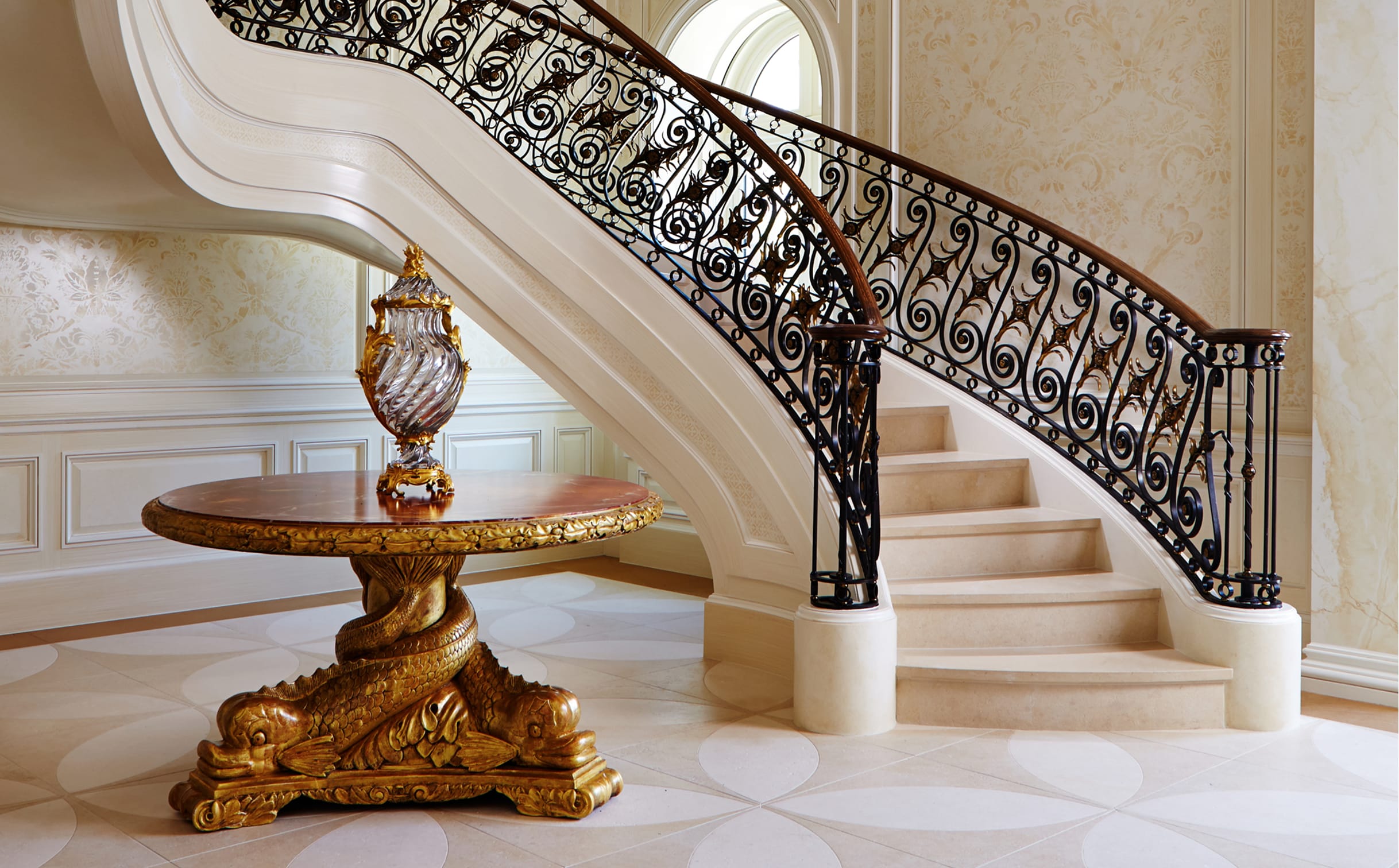 Curved staircase with an ornate railing and wood handrail, in a formal interior