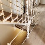 Closeup of a floating staircase with open wood treads and multi-line railing