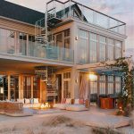 Multi-Line spiral staircase on a coastal home exterior, connecting a patio to a rooftop deck at dusk