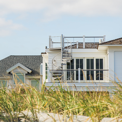 Outdoor spiral staircase in a white finish on a beach house, connecting a deck to a rooftop terrace