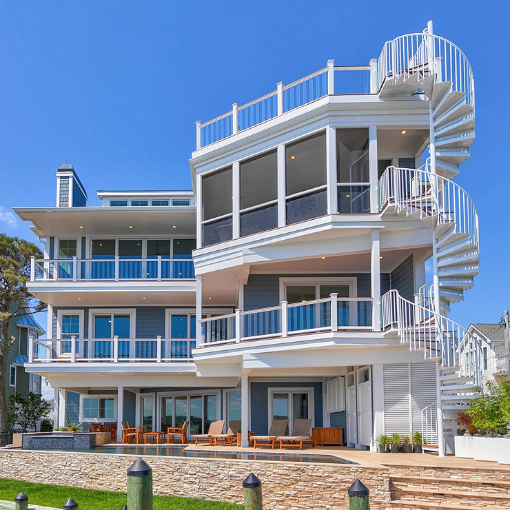 White exterior spiral staircase connecting multiple deck levels on a waterfront home, with a pool and dock below