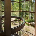 Close view from beside a curved glass elevator shaft, looking out through floor-to-ceiling glass panels