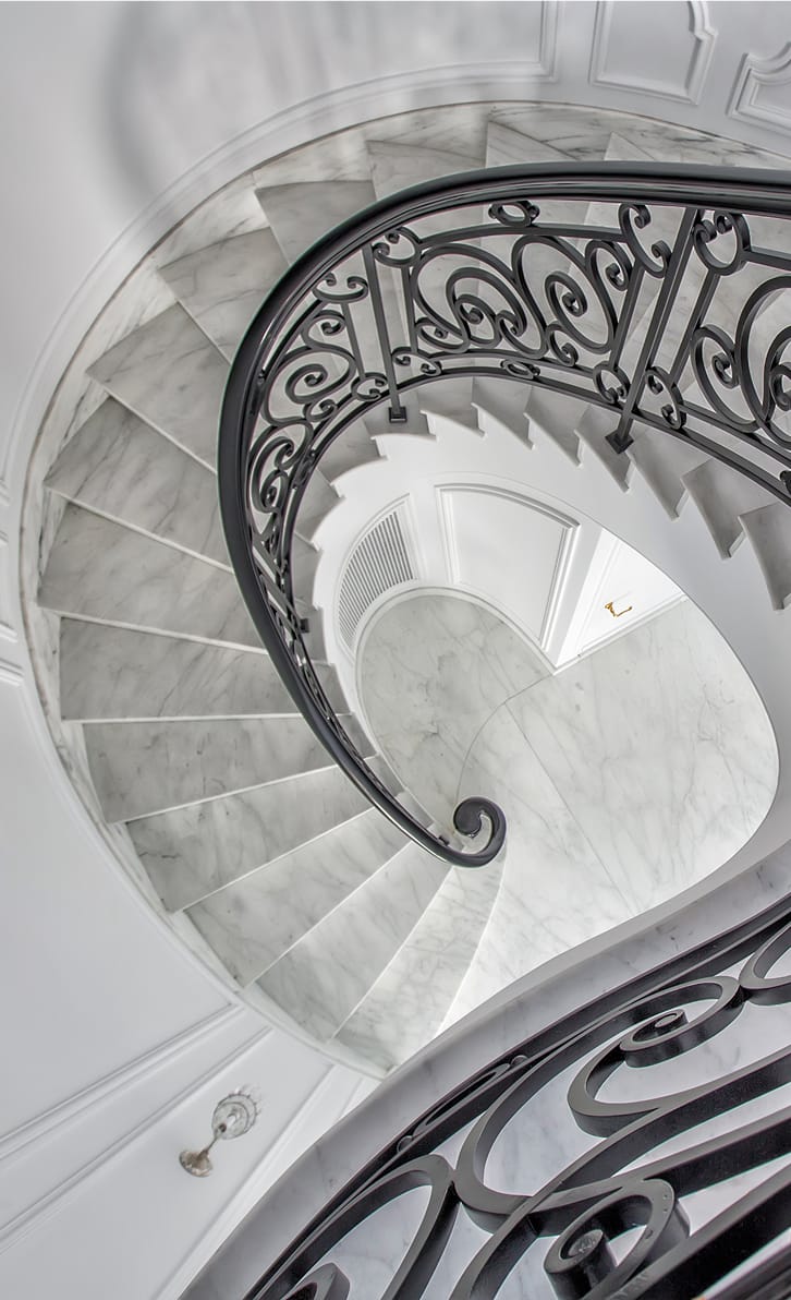 Custom curved, cantilevered stair with rolled, hand forged steel guardrails and wood handrails