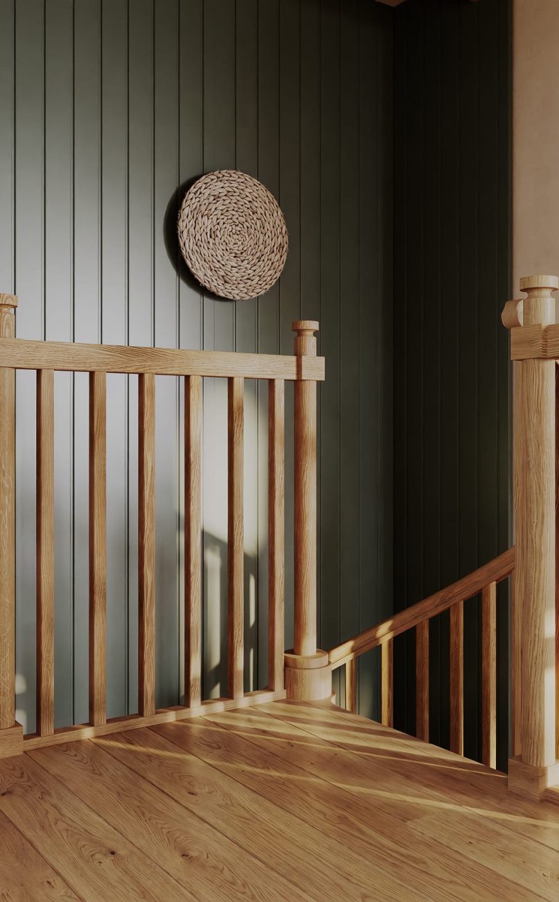 Close-up of an oak spiral staircase landing with spindles, a newel post, and a woven wall basket against a green paneled wall